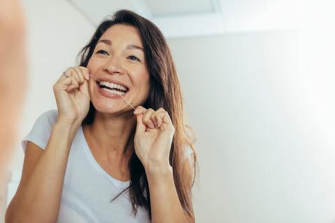 Mujer utilizando el hilo dental después del cepillado.