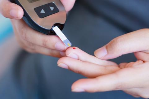 Persona midiendo sus niveles de glucosa con un glucómetro para identificar un posible pico de glucosa.