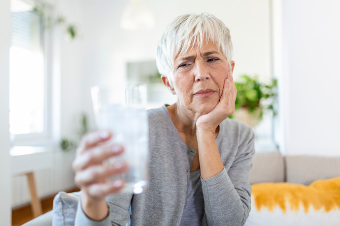 Mujer con dientes sensibles que necesita una limpieza dental.