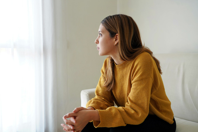 mujer sentada mirando por la ventana