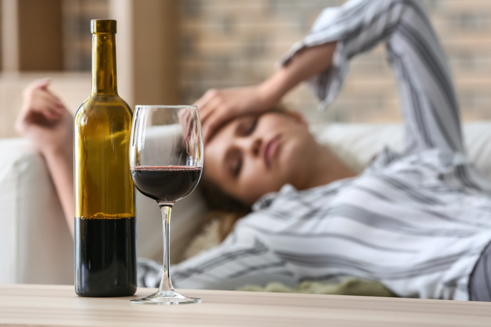 Mujer con copa de vino a la que le sienta mal el alcohol.