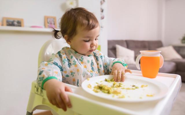 Niña pequeña comiendo en su silla alta