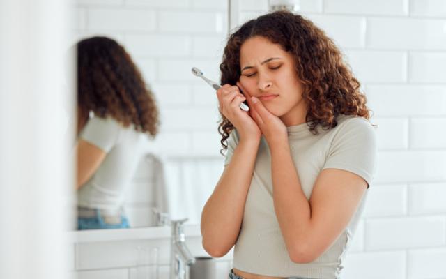 Chica con dolor de muelas por no saber cómo prevenir las caries. 