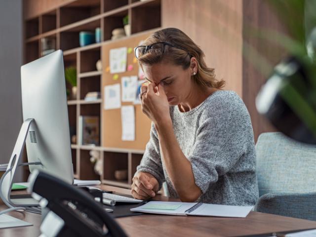 Mujer quejándose del dolor de cabeza por el burnout.